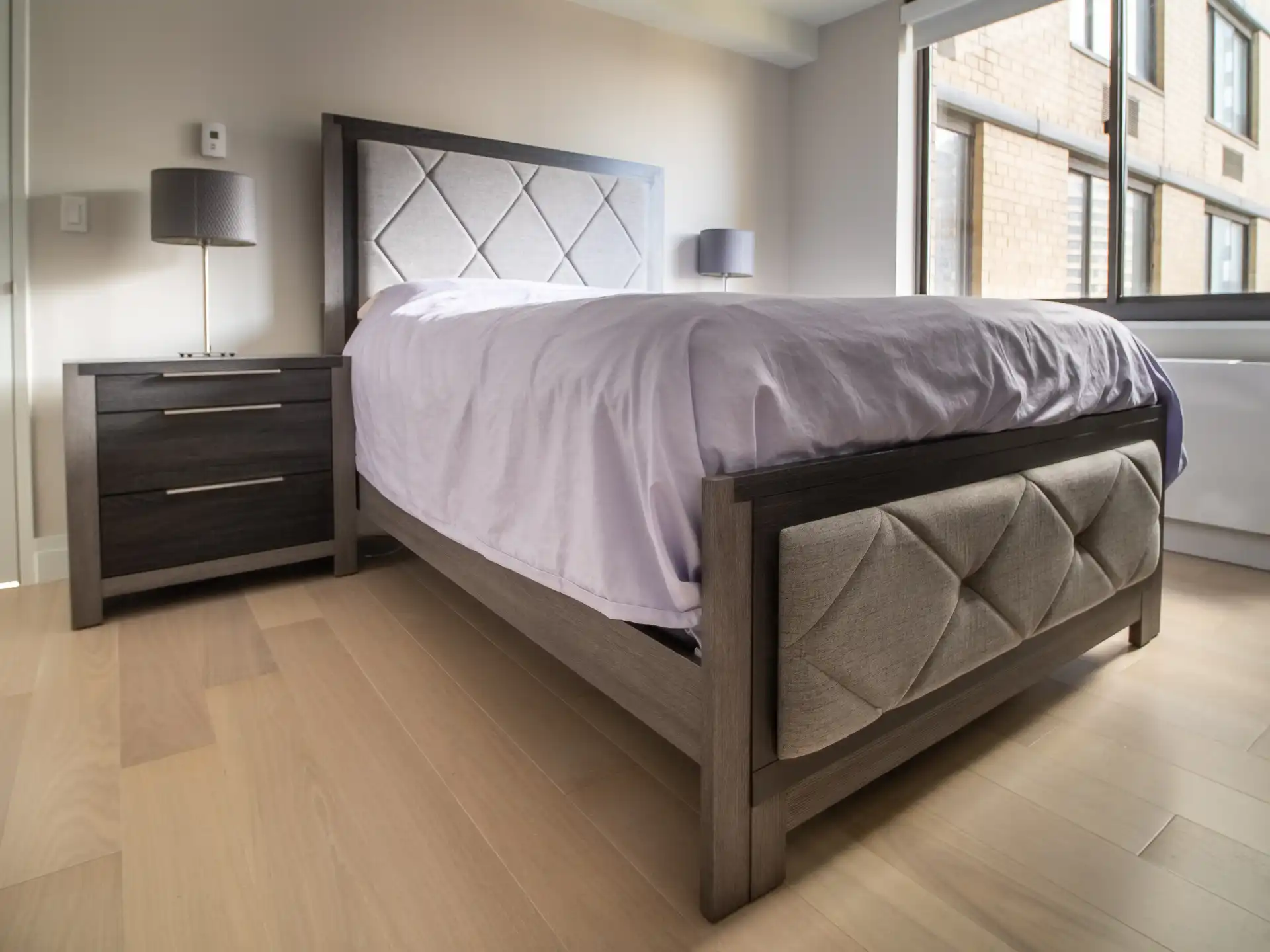 Slaapkamer met gestoffeerd bed en warme houten vloer